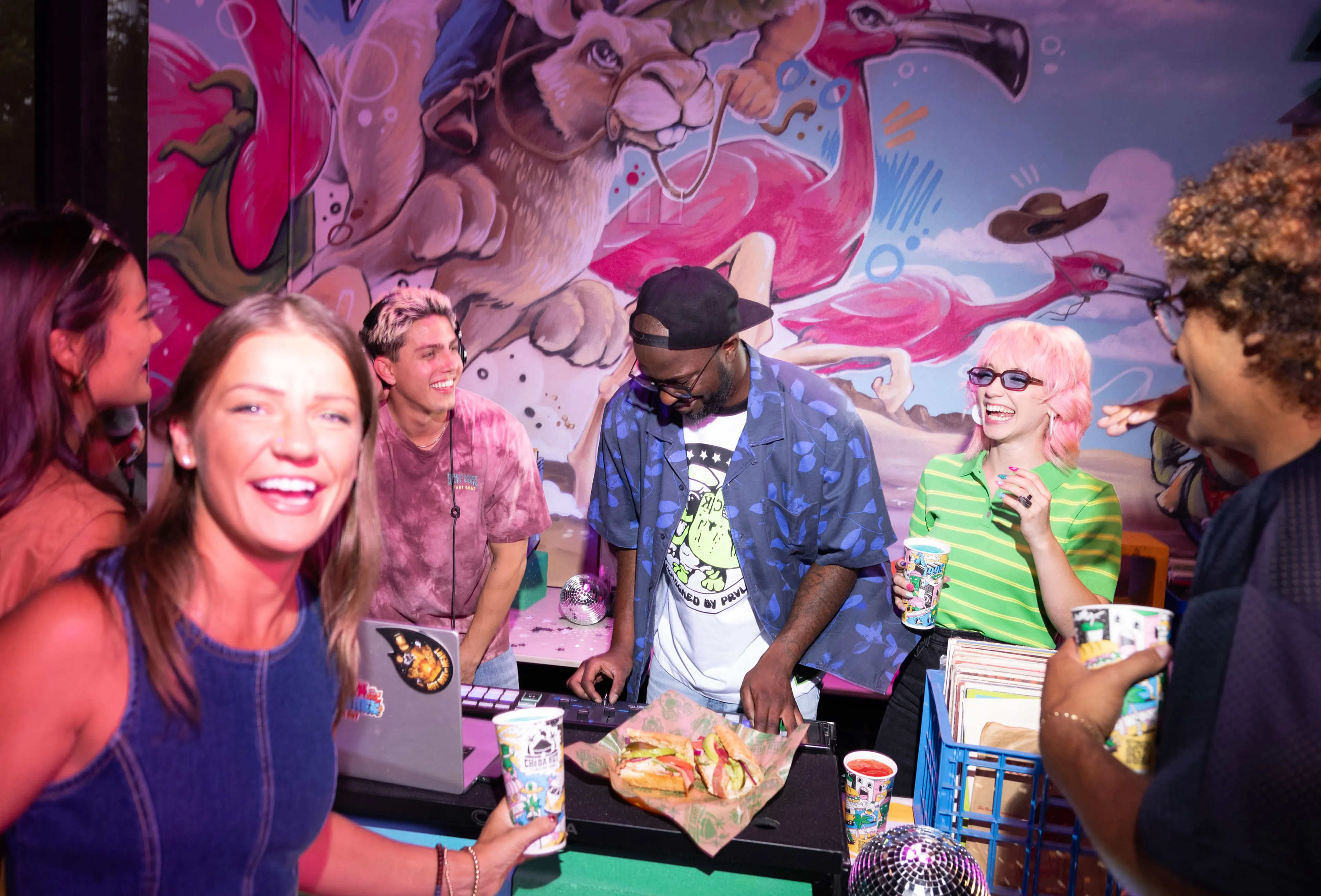 People enjoying Cheba Hut Toasted subs and drinks at a party with a DJ