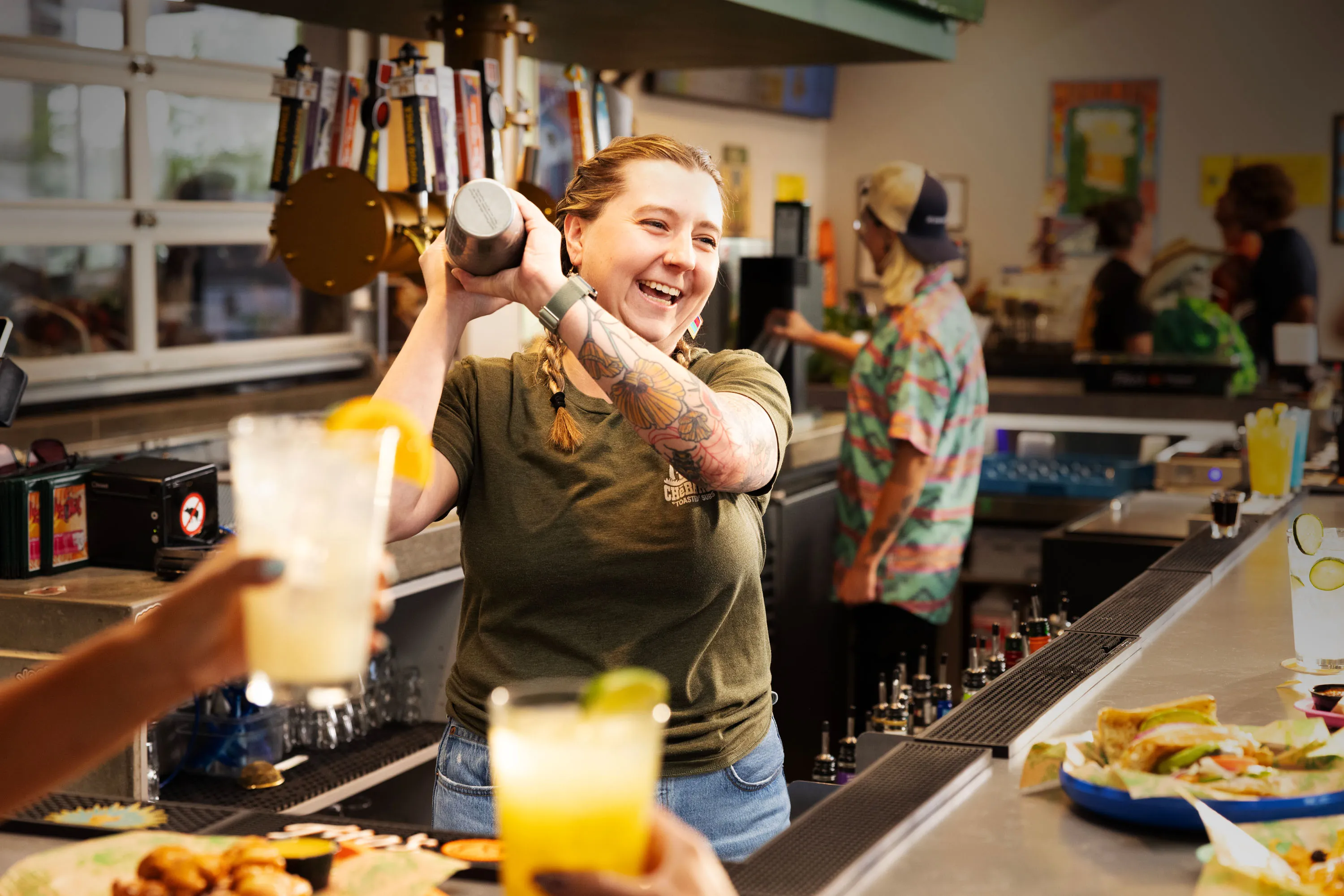 Bartender shaking a cocktail behind the bar while drinks and food are served