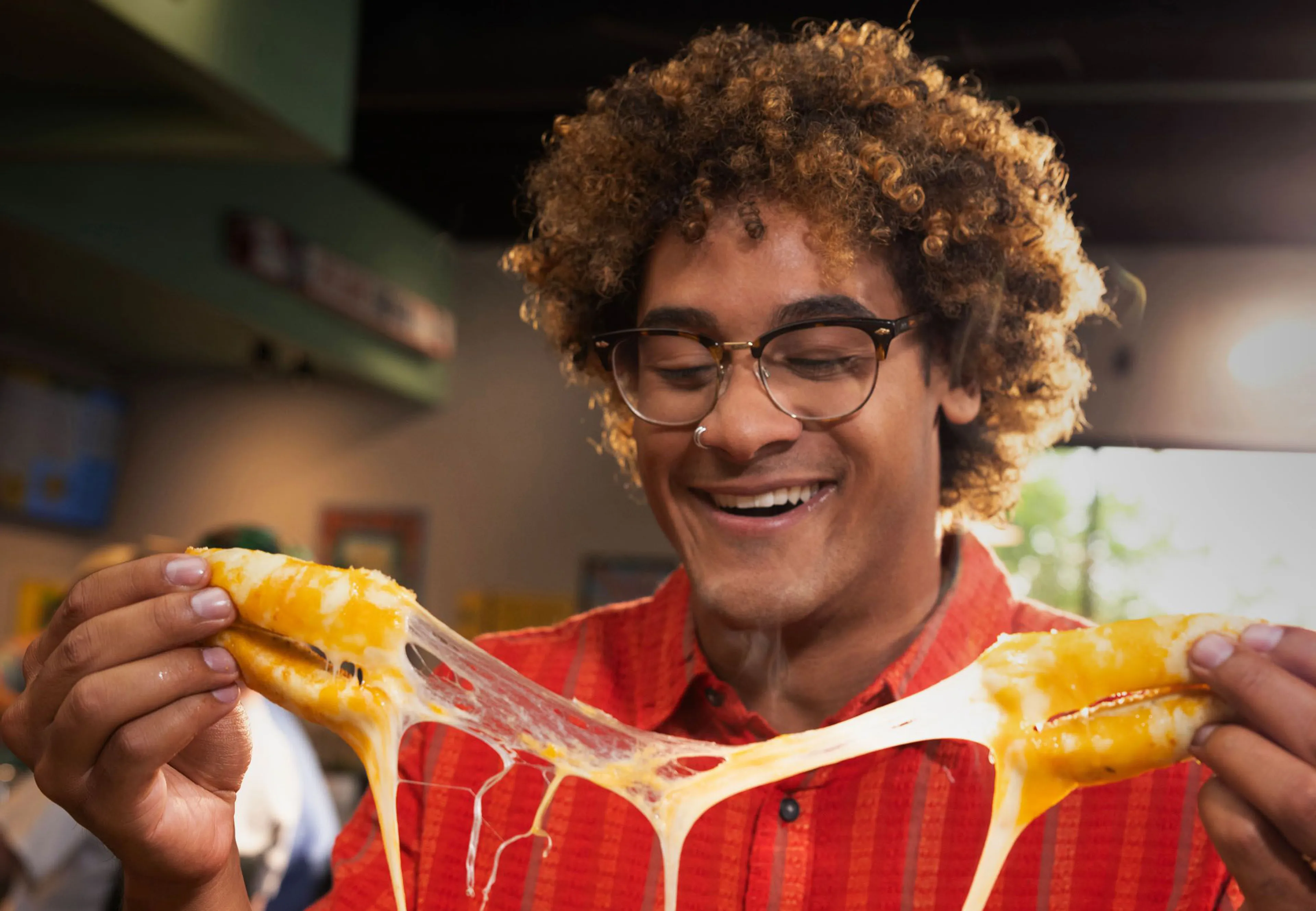 Person stretching melted cheese from a loaded Cheba Hut snack